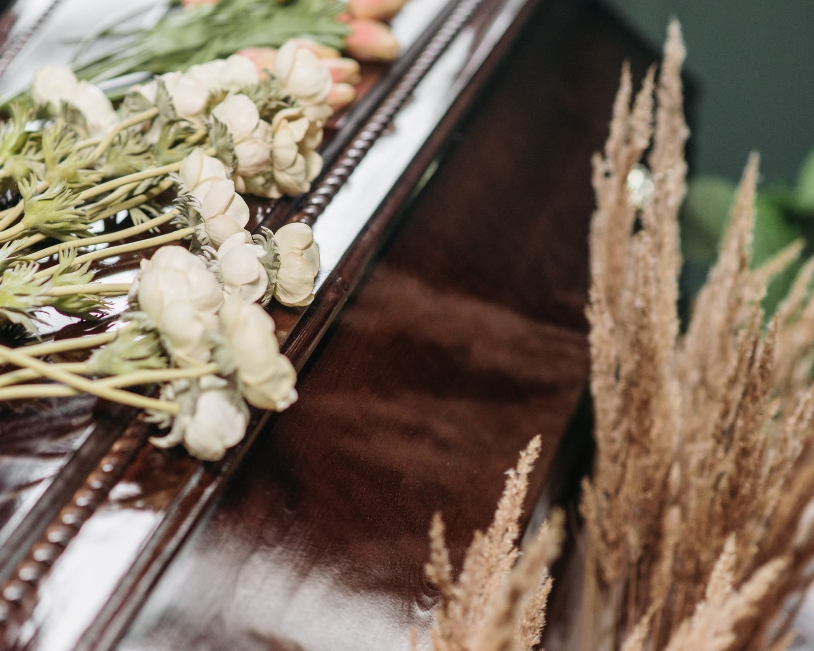 White flowers arranged along a polished wooden casket.